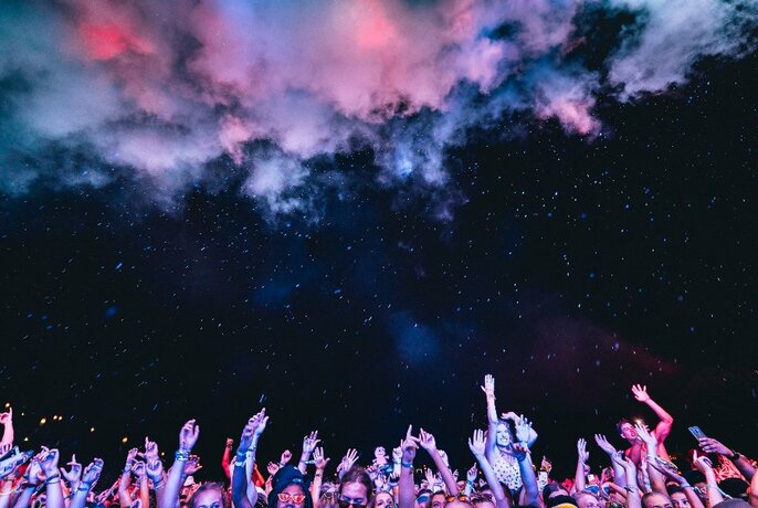 Night sky above trees and festival crowd.