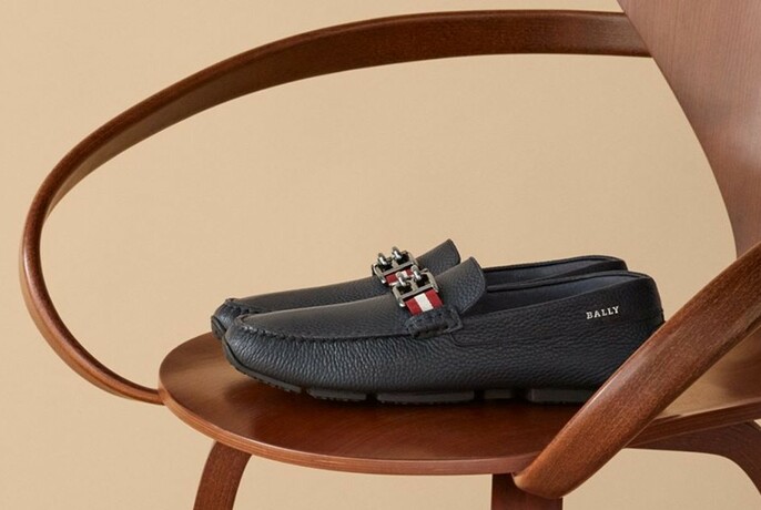 A pair of dark blue loafers on a wooden chair. 