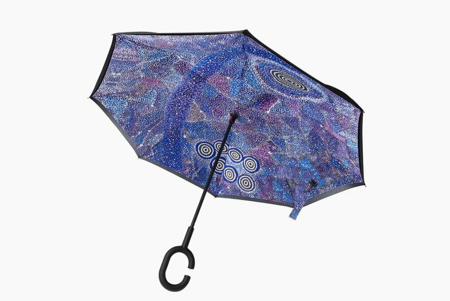 A black and purple umbrella with a hook handle and Aboriginal artwork on the inside. 