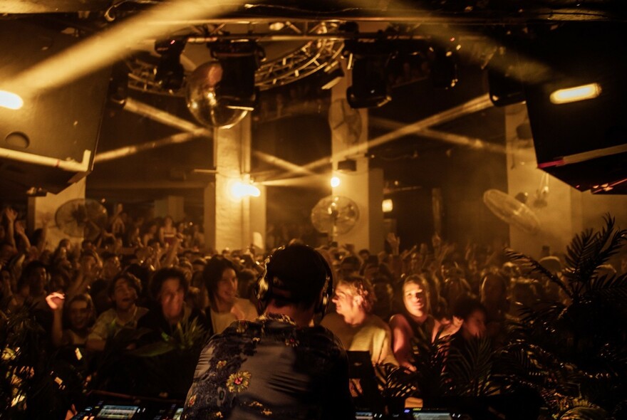Crowded nightclub with spotlights and DJ.