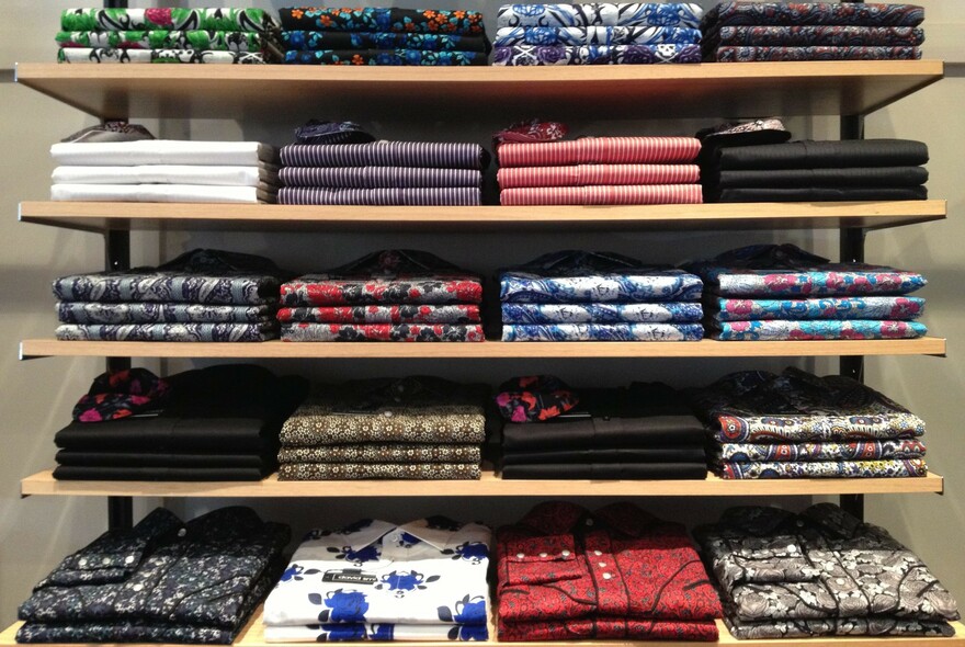 Men's clothing neatly arranged on shelves in Jay Dillon fashion menswear store.