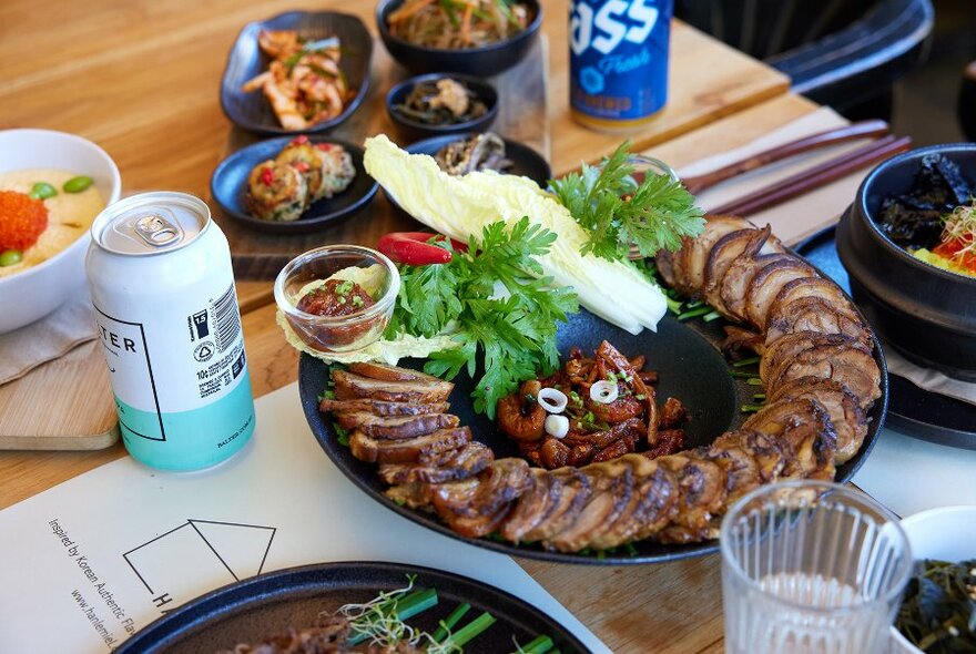 A restaurant table set with Korean dishes and cans of beer.
