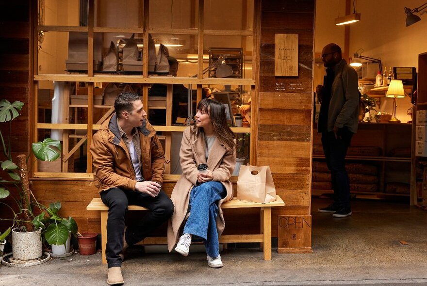 Two people are sitting in front of a small cafe