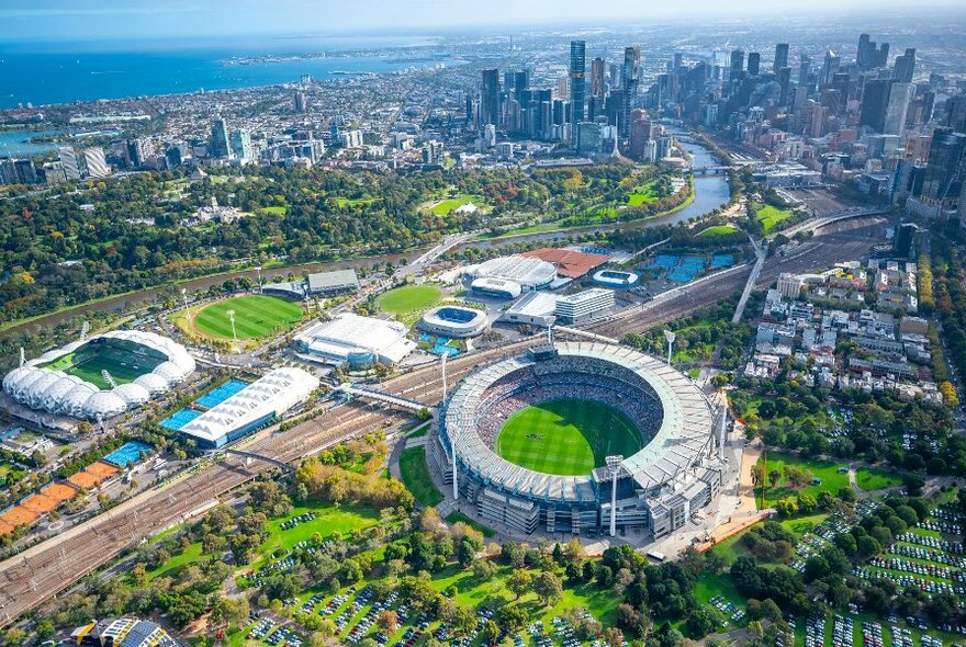 An aerial shot of Melbourne city with the MCG in the foreground on a sunny day.