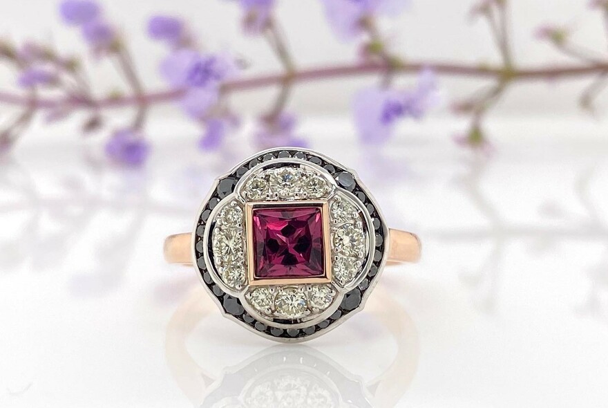 Antique-style ring with square-cut red stone surrounded by diamonds.