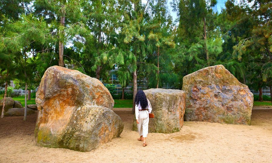 A woman looking at the large carved ancestor stones of Birrarung Wilam.