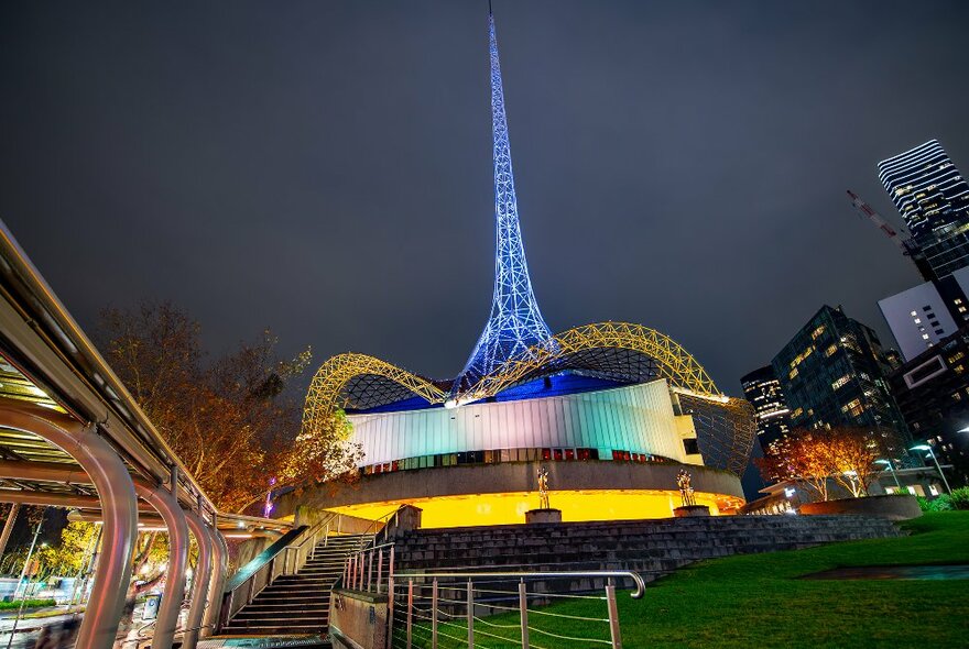 A modern theatre at night with a tall blue spire