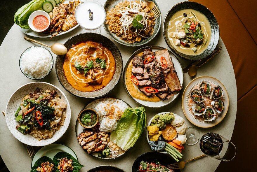 Looking down on a round table with many Thai dishes displayed