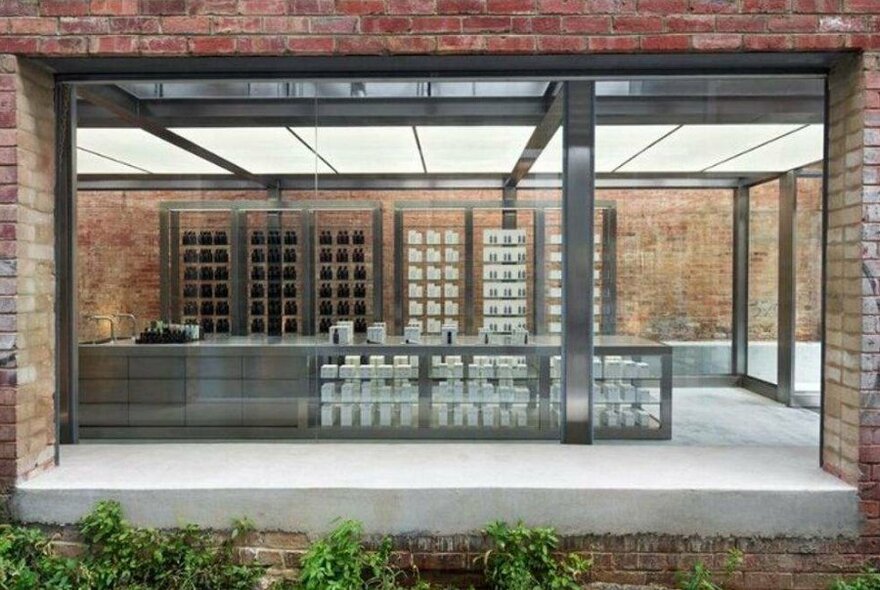 The exterior of a minimalist beauty store with bricks and metal shelving.