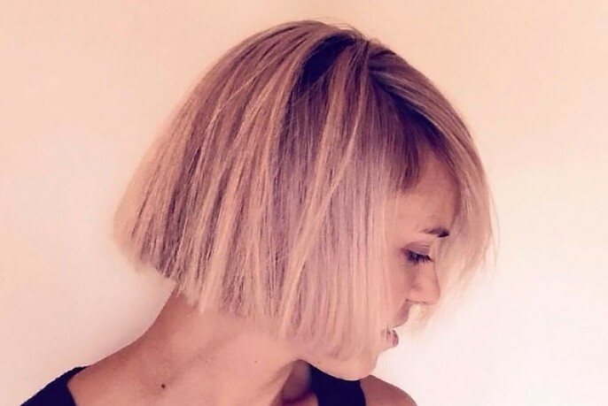 Rosy tinted profile view of a woman with a blunt haircut. 