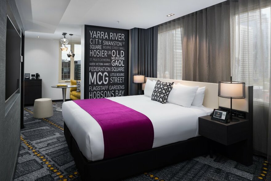 A bedroom suite at the Pullman Melbourne City Centre, with king size bed, bedside tables and lamps, and artwork on the walls.