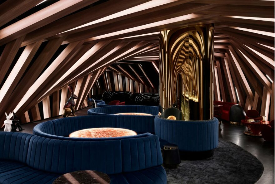 A futuristic cocoon-like space with blue velvets couches and low lighting. 