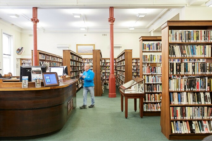 Person approaching the desk in Melbourne Athenaeum Library.