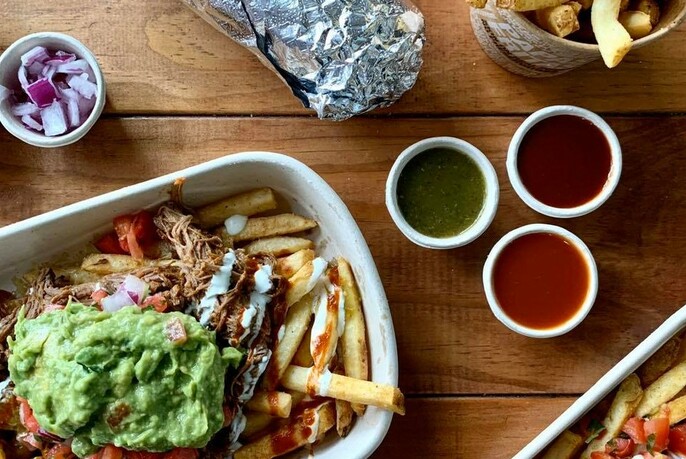 Loaded fries with guacamole and three different coloured dipping sauces. 