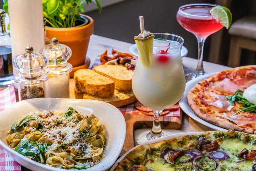 Cocktails and pizzas on a table at a restaurant