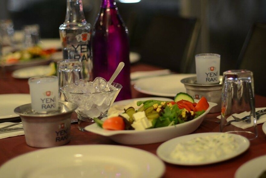 Mediterranean salads and dips with raki bottle and glasses.
