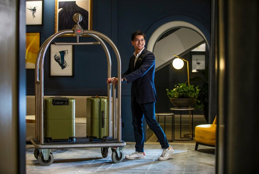 A hotel porter pushing a luggage trolley through the lobby of Voco Melbourne Central.