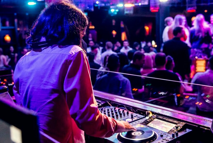 A DJ on the decks in a busy nightclub.