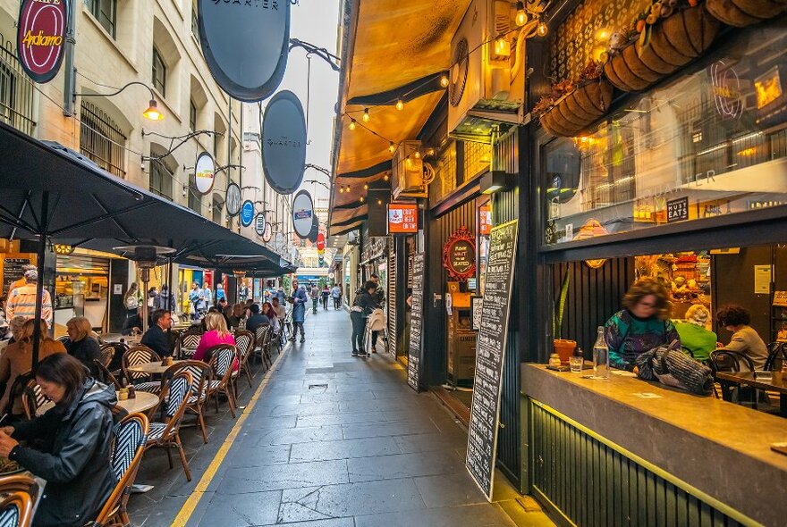A laneway with outdoor cafe seating under umbrellas. 