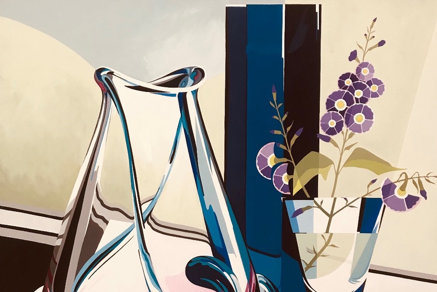 A still life showing an empty glass vase with a smaller vase containing purple flowers. .