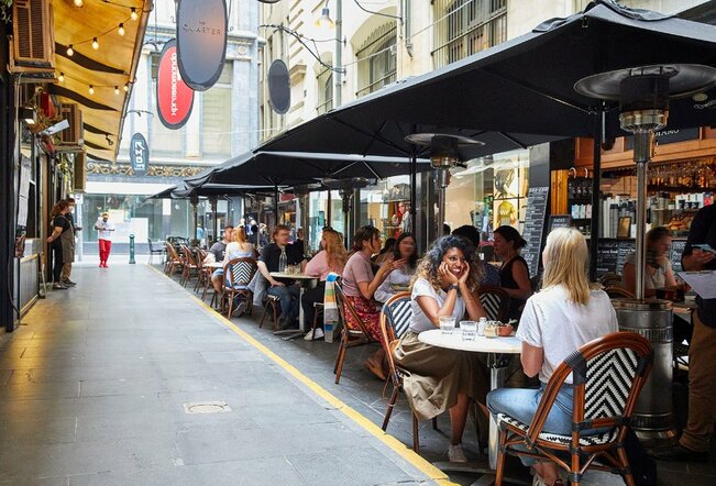 A busy laneway with people dining at outdoor tables.