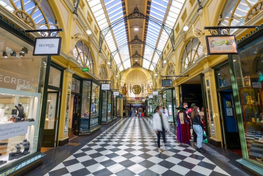 A shopping arcade with black and white tiles, shoppers and a witch.