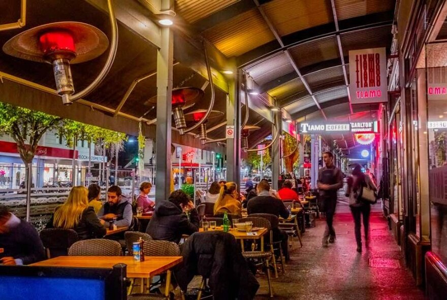Outdoor diners under gas heaters on Lygon Street.