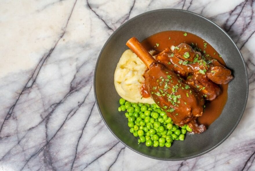 Meal in a pan with meat, mash and peas. 