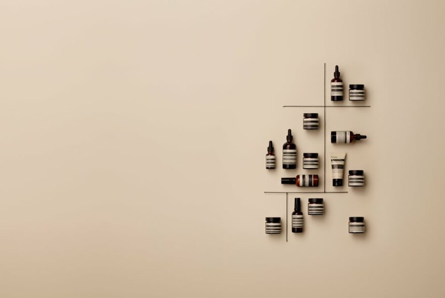 A small arrangement of Aesop products at various angles on a beige wall. 