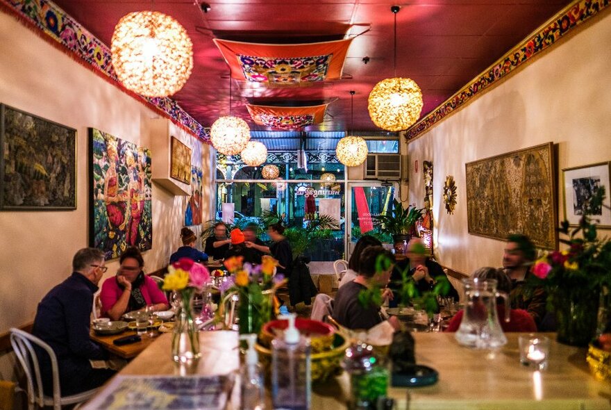 A busy restaurant with colourful decor and pendant lights.
