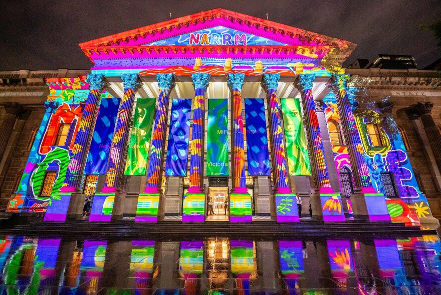 State Library Victoria portico and facade illuminated for Christmas in blue, green and pink details.