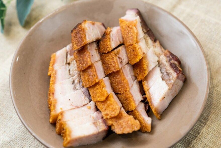 A brown dish with slices of pork.