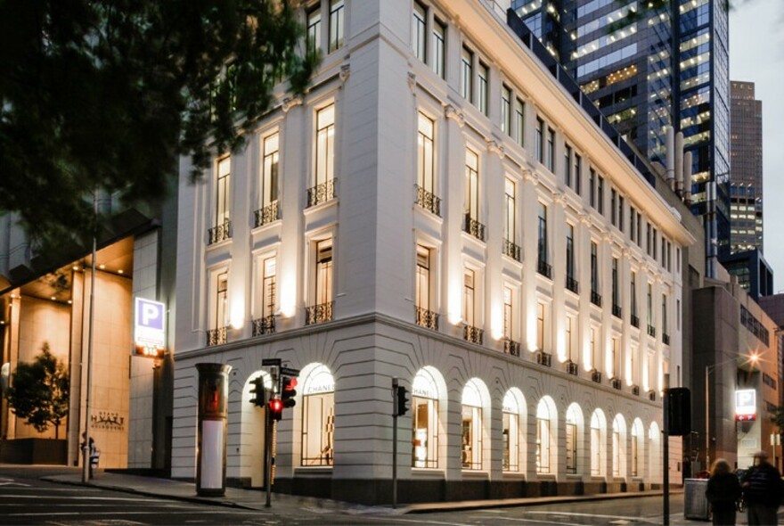 Exterior of Chanel's Melbourne headquarters, white four-storey building on a corner, with arched windows on ground floor.