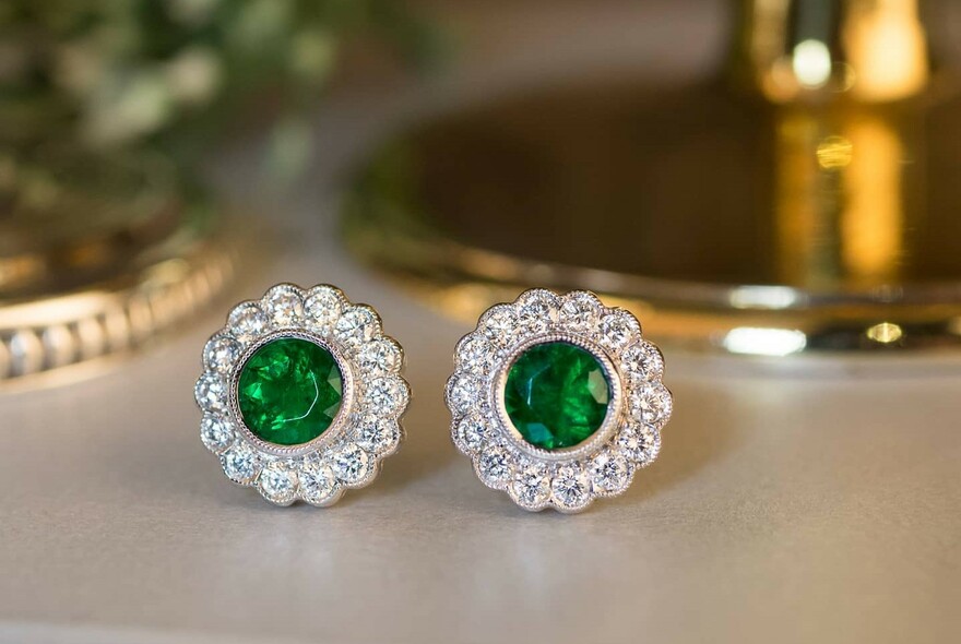 Round emerald and diamond stud earrings.