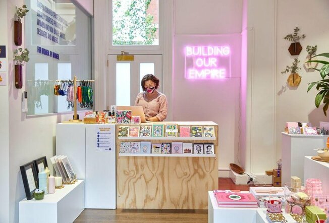 The inside of a small Melbourne shop with pink neon sign that reads building our empire. 