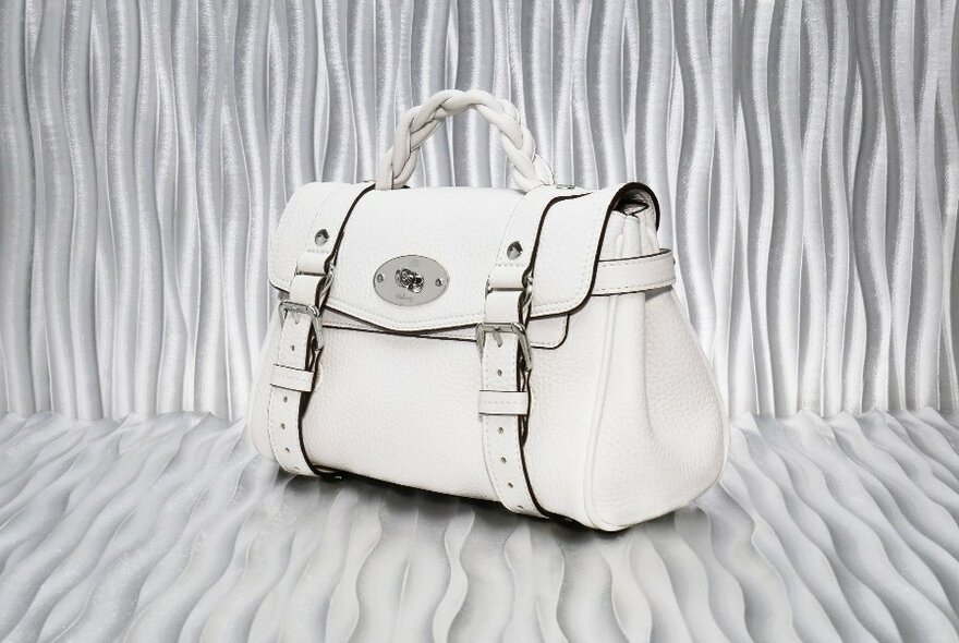White leather handbag with distinctive Mulberry logo, against a textured white backdrop.