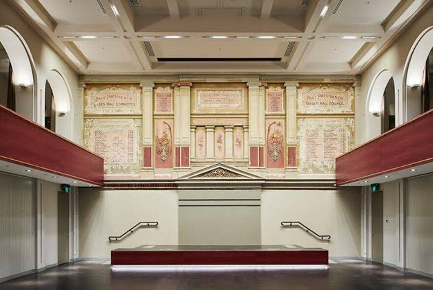 Trades Hall chamber with mezzanine area and central fresco of pillars and details.