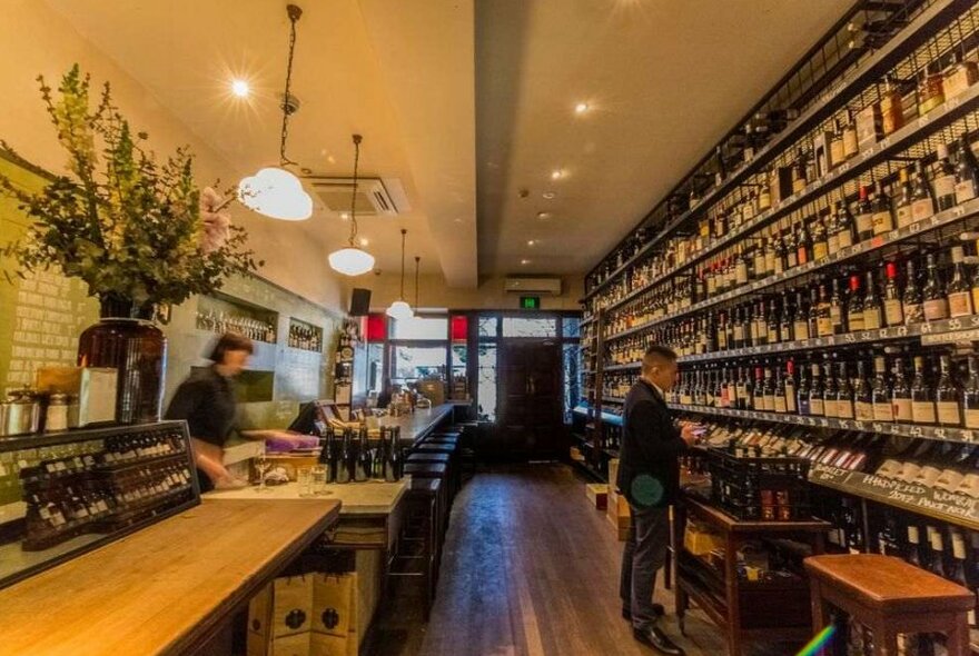 A man browsing the wall of wines at a wine bar.