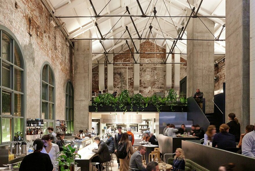 A busy cafe with plants, brick walls and high ceilings.