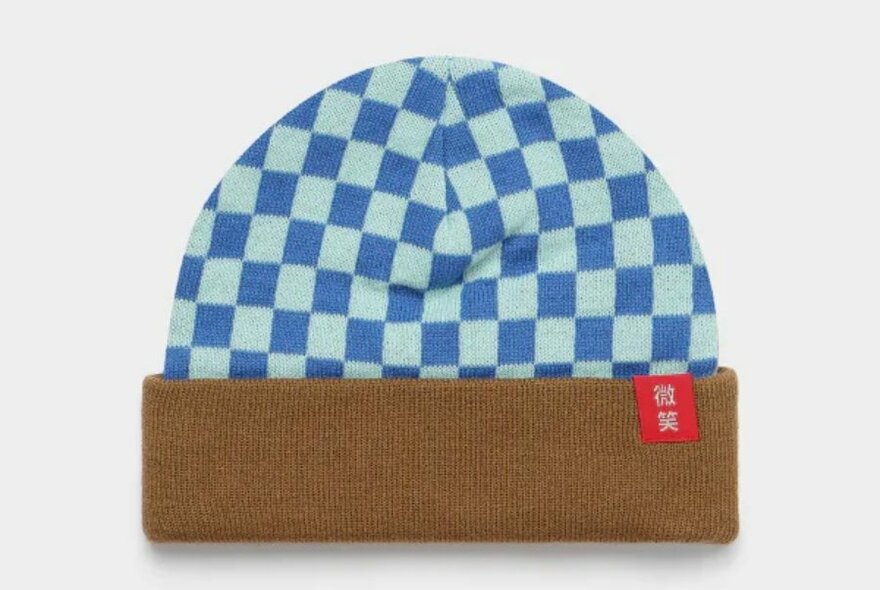 A blue checked beanie with a brown cuff and red tag.