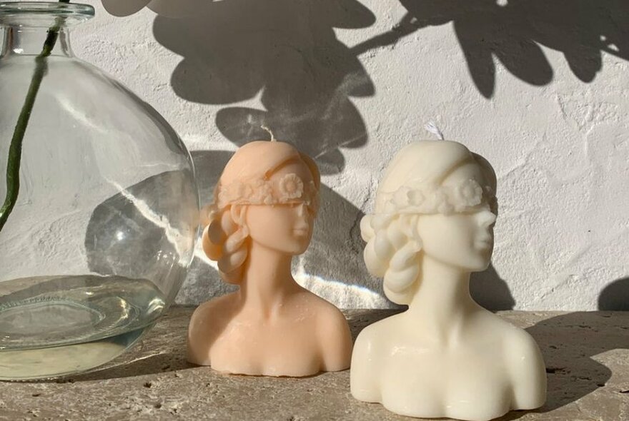 Wax candles in the shape of busts of a head and shoulders.