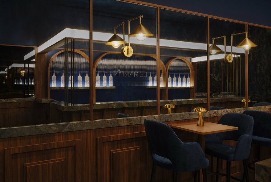 The pop-up bar Le Martini, showing the marble bar service area, a row of vodka bottles on the rear shelf, and soft hanging lights.
