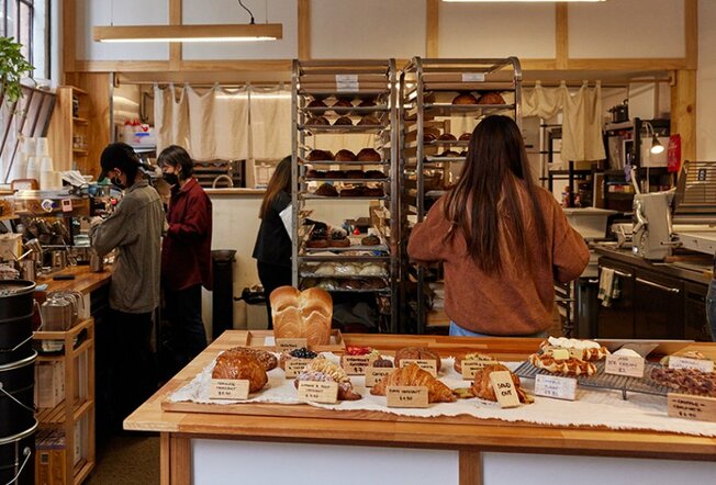Cafe workers busy behind a counter with bread and pastries.