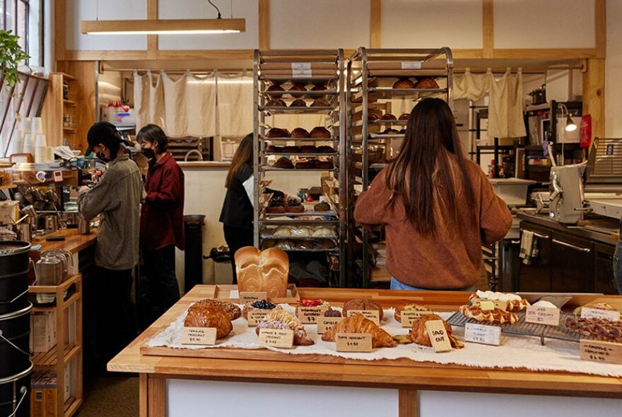 Cafe workers busy behind a counter with bread and pastries.