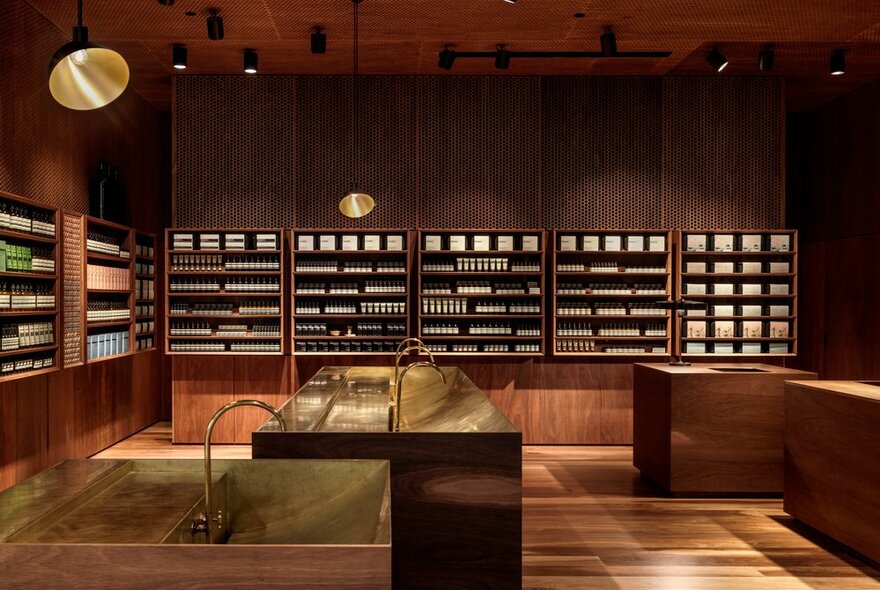 The warm wood interior of an Aesop shop with products on shelves.