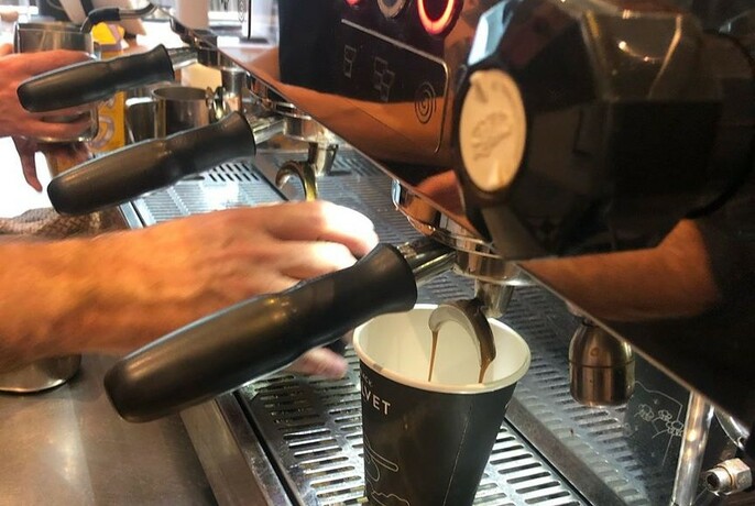Close-up of barista's hands making coffee at an espresso machine.