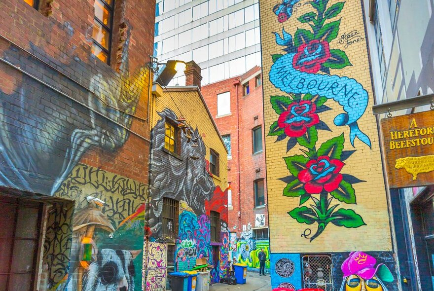 A mural in a city laneway with roses and a banner reading Melbourne.