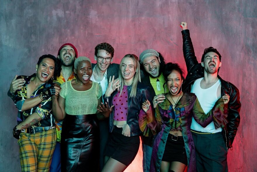 The cast of Rent in colourful costumes.