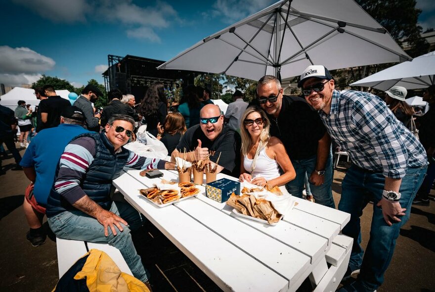 People seated at a table under umbrellas with food.