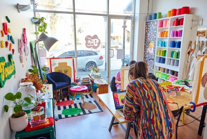 A woman working in a colourful craft studio.